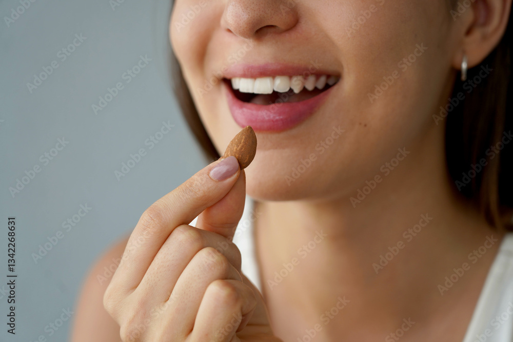 Almond Unpeeled. Close-up of unidentified girl eating a almond seed. Healthy food concept.