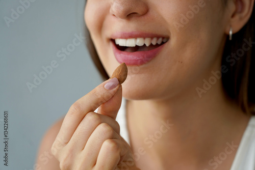 Obraz na płótnie Almond Unpeeled. Close-up of unidentified girl eating a almond seed. Healthy food concept. w salonie