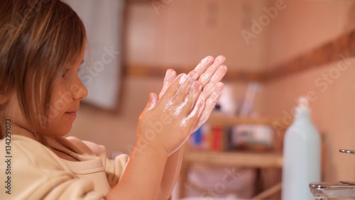 Girl washing her hands in a bathroom sink, creating soapy bubbles, emphasizing hygiene and health