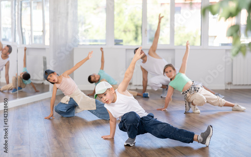 Portrait of active teen boy enjoying modern energetic dancing in group at street dance studio