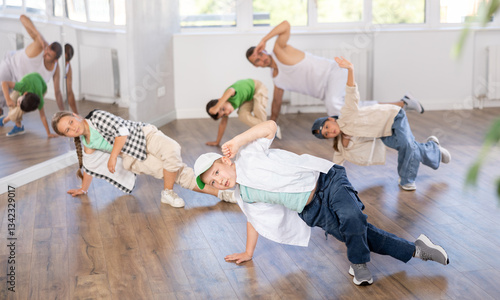 Positive boy and teens doing breakdance in dance hall with male trainer in light choreography studio