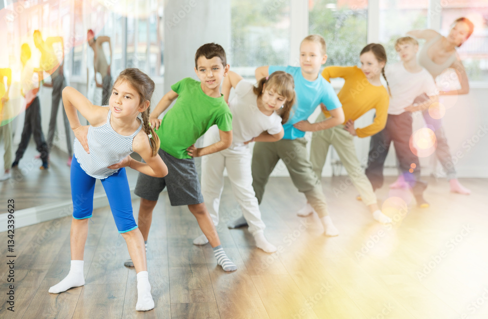 Naklejka premium Happy smiling preteen dancers practicing dance routine with female choreographer in modern studio
