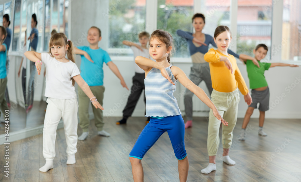 Obraz premium Group of happy preteen children with female teacher practicing hip hop in modern dance studio