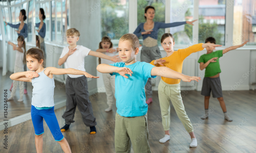 Obraz premium Boy with friends repeat teaches sequences of movements during training, train to perform electro dance, enjoys active hobby to her favorite music. Unrecognizable female teacher administer conduct