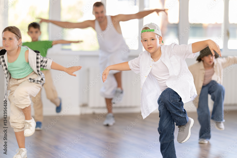 Naklejka premium Active children practicing hip-hop dance in training hall during group dancing classes
