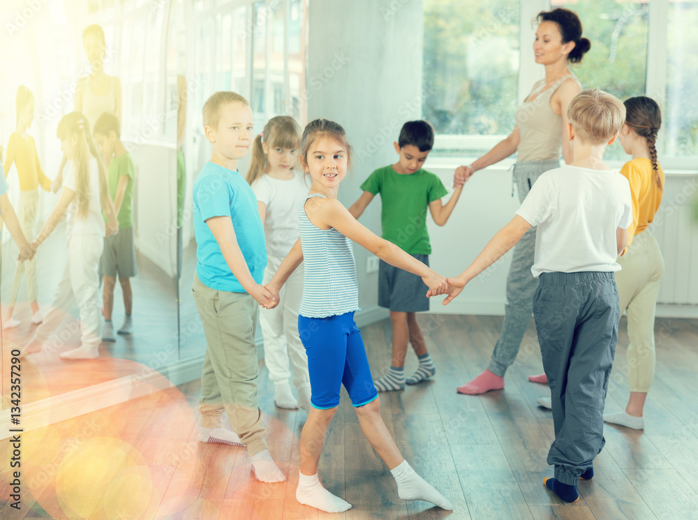 Boys and girls holding hands perform incendiary traditional roundelay folk dance during rehearsal in studio. Boys and girls holding hands perform incendiary traditional roundelay folk dance during rehearsal in studio.