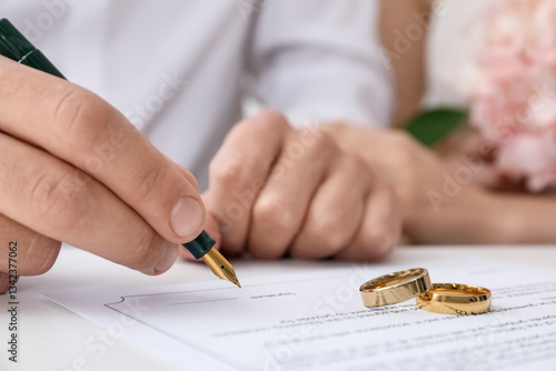 Фотография Newlyweds signing marriage contract and wedding rings on desk, selective focus