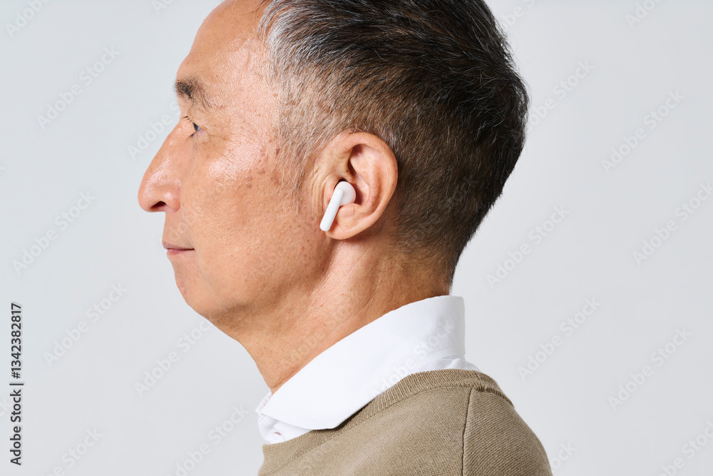 ワイヤレスイヤホンを使う私服姿のシニア男性 ワイヤレスイヤホンを使う私服姿のシニア男性
