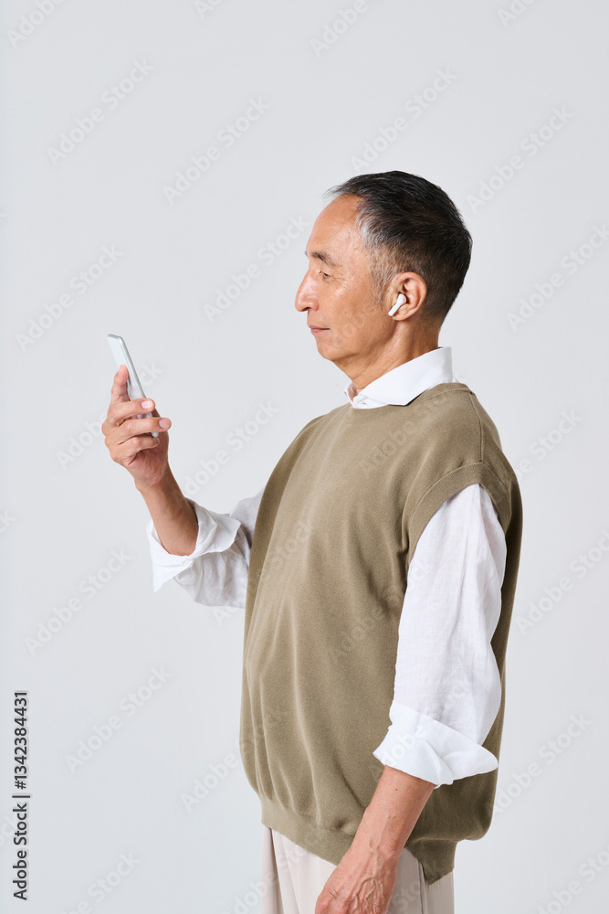 スマートフォンで音楽を聴く私服姿のシニア男性 スマートフォンで音楽を聴く私服姿のシニア男性