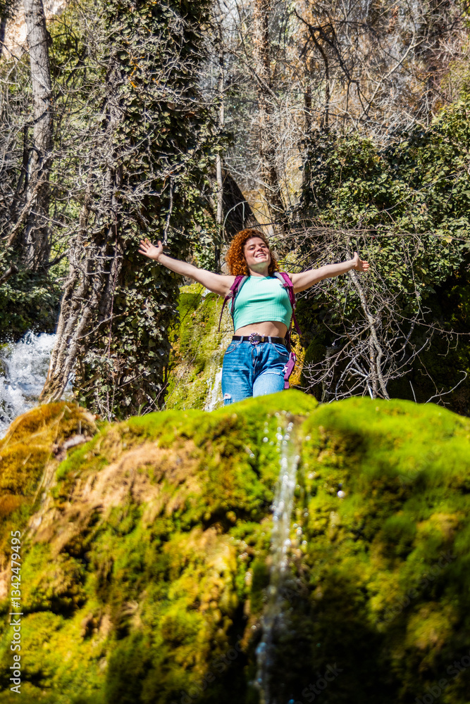 Fototapeta premium Tourist enjoying freedom in wild nature with open arms near waterfall