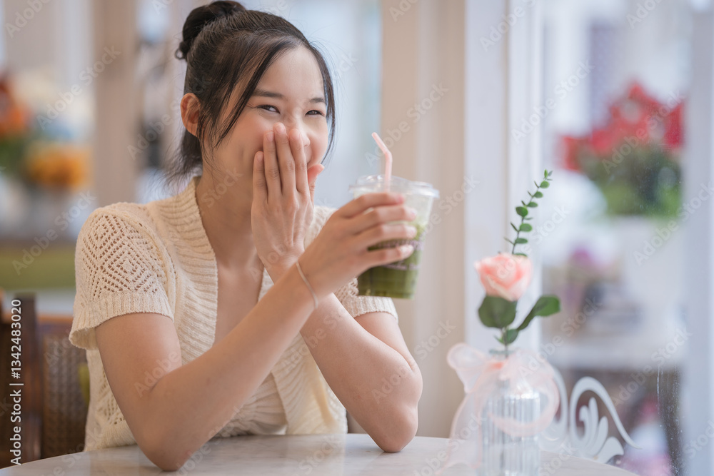 Pretty Asian woman travelers are holding a Matcha latte green tea with cold refreshing drinks, enjoying a peaceful moment of wellness relax, wearing modern Handwoven Fabric and blue jeans. Pretty Asian woman travelers are holding a Matcha latte green tea with cold refreshing drinks, enjoying a peaceful moment of wellness relax, wearing modern Handwoven Fabric and blue jeans.