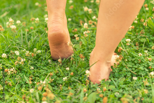 Close-up of heels lifting from a grassy field with small wildflowers.