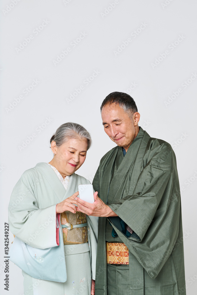 Fototapeta premium 一緒にスマートフォンを使う着物を着たシニア夫婦