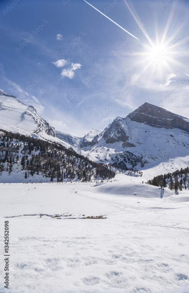 Fototapeta premium People walking across winter mountain landscape on a sunny day