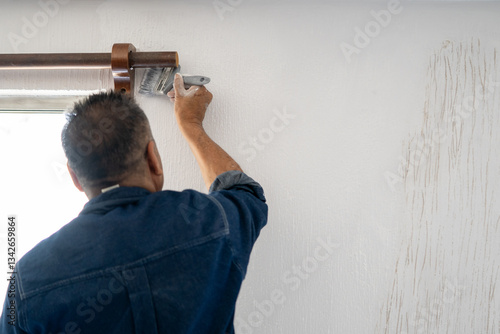 hombre pintando pared con brocha y pintura blanca