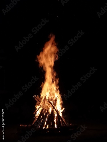 A blazing bonfire illuminates the darkness, with flames reaching towards the night sky