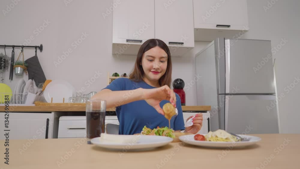 Asian attractive female eating green salad and spaghetti in kitchen room. Asian attractive female eating green salad and spaghetti in kitchen room.
