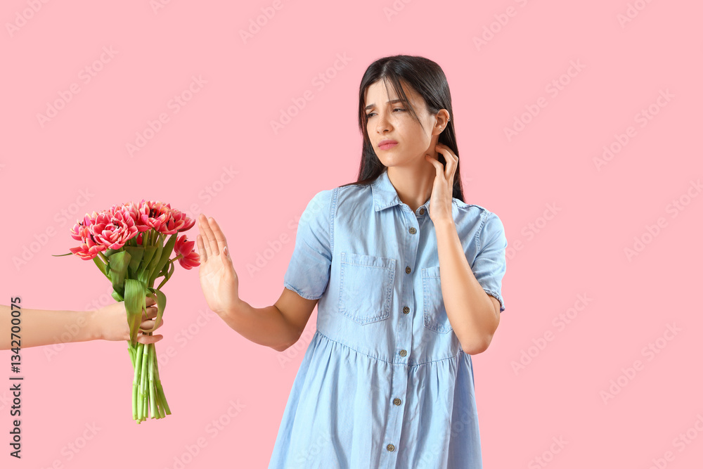 Allergic young woman rejecting tulips on pink background Allergic young woman rejecting tulips on pink background