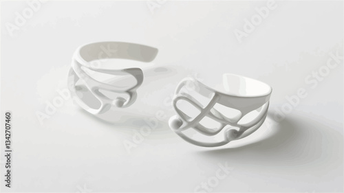A close-up studio shot depicts a pair of white, openwork rings arranged on a white background. The rings have a minimalist design with cut-out patterns.  The image is sharply focused, showcasing