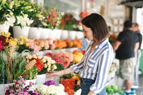 Slika na platnu Woman browsing colorful flowers at a market