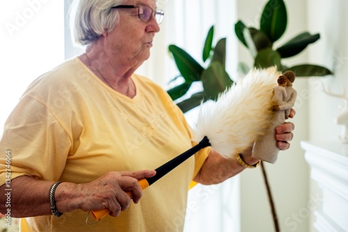 Wall Mural Elderly woman dusting a figurine with a feather duster