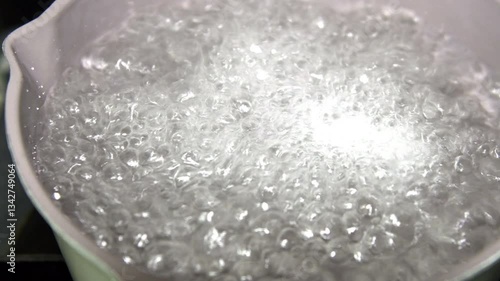 Closeup of boiling water in kitchen pan on stove top.