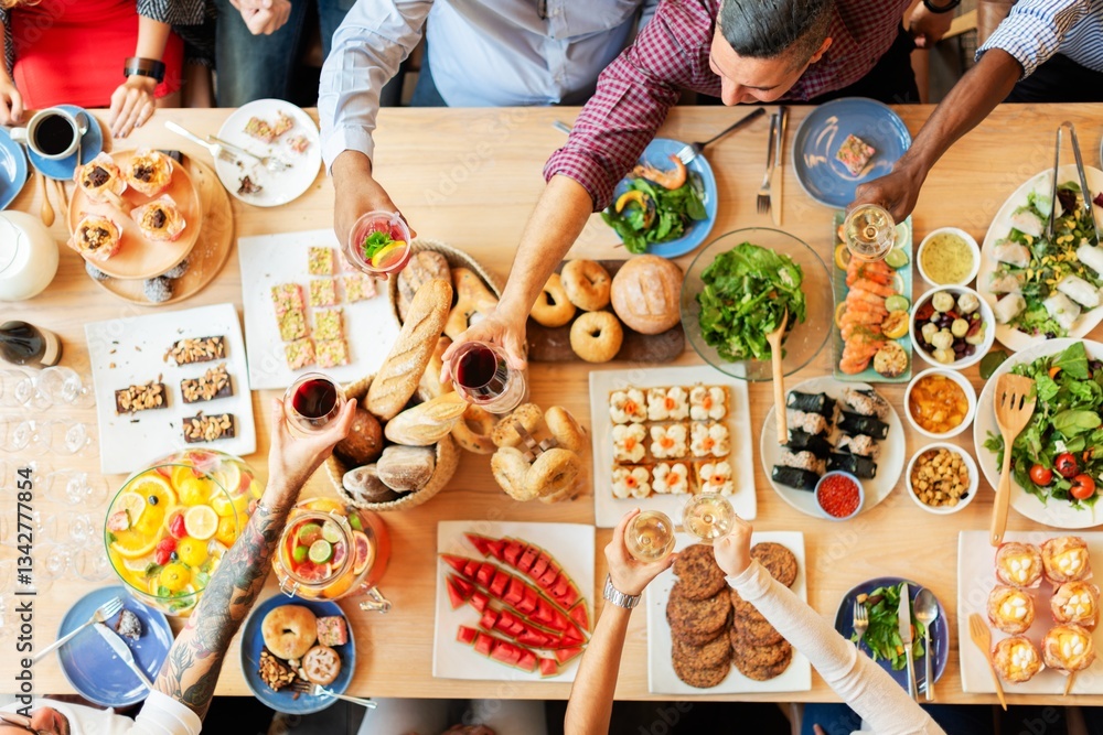 Top view of a diverse group enjoying a meal. People share food, toast drinks, and celebrate. A variety of dishes and drinks on a wooden table. Buffet table with delicious food photo from top view.