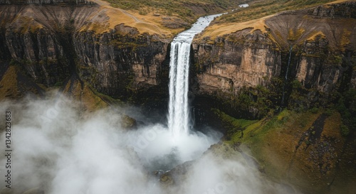 Majestic waterfall cascading down rocky cliffs surrounded by lush greenery and mist