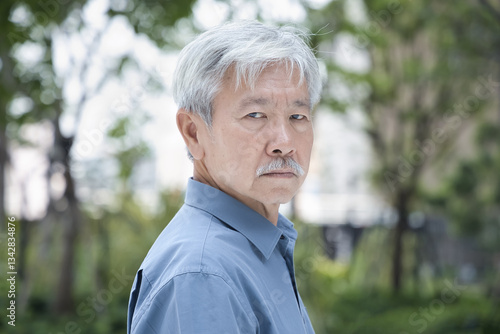 Serious and worried old senior Asian man look back over his shoulder, with bad negative mood