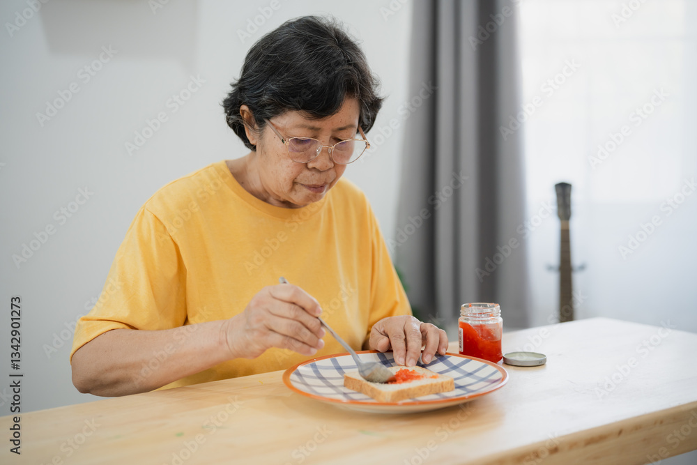 Senior Asian woman enjoying breakfast with toast and jam in cozy kitchen setting, health-conscious lifestyle, natural lighting, and simple tableware Senior Asian woman enjoying breakfast with toast and jam in cozy kitchen setting, health-conscious lifestyle, natural lighting, and simple tableware