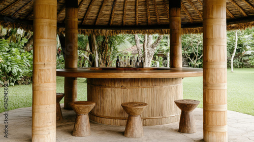 A rustic open-air wooden pavilion with a circular layout, featuring a woven straw roof and sturdy bamboo pillars