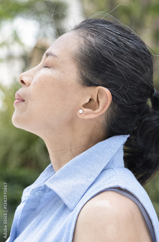 Happy relaxed refreshing old retired senior Asian woman breathing, inhaling clean unpolluted air in urban park, good summer, summer wellness, sunlight exposure concept image Happy relaxed refreshing old retired senior Asian woman breathing, inhaling clean unpolluted air in urban park, good summer, summer wellness, sunlight exposure concept image