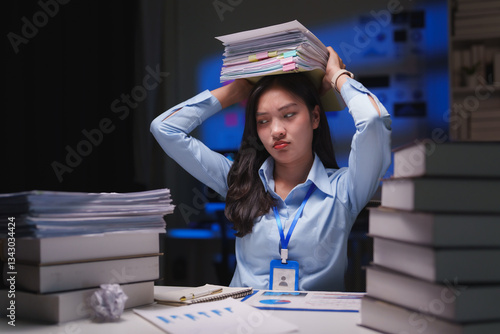 Young office worker holding a heavy stack of paperwork on her head while working late at night, expressing frustration and exhaustion from overwork and dealing with a large amount of files