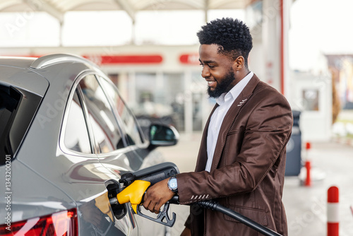 Papier peint Smiling interracial man filling up car tank at gas station.