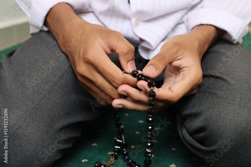 фотографія A close-up front Hand of a religious Muslim man reciting dhikr with a prayer beads in his hand