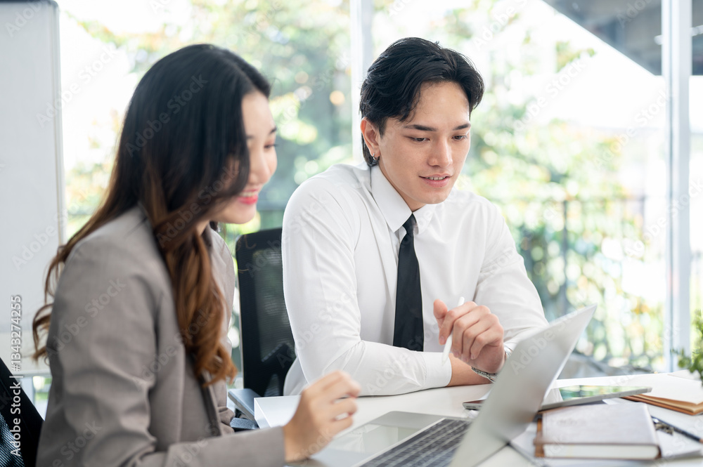 Female office worker and her male coworker is smiling while talking together at the working desk. Female office worker and her male coworker is smiling while talking together at the working desk.