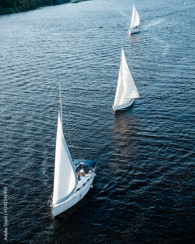 Obraz na plátně Aerial view of three yachts sailing down a river on a sunny afternoon