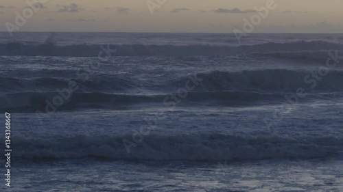 Ocean waves crashing against the coast after sunset in Caparica