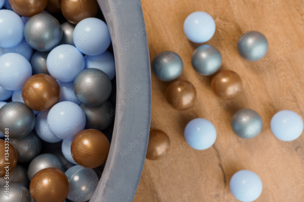 Multicolored Plastic Balls Scattered Around and Inside Soft Play Pit on Wooden Floor from Above