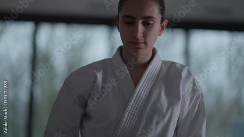Woman training Karate in the dark, with big windows in the back