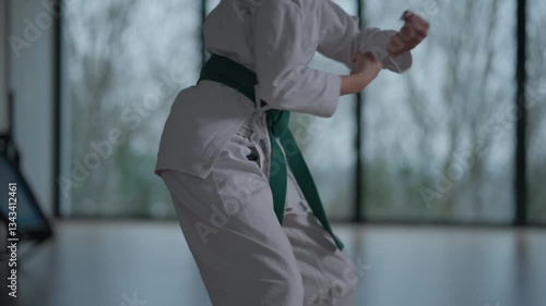 Woman training Karate in the dark, with big windows in the back