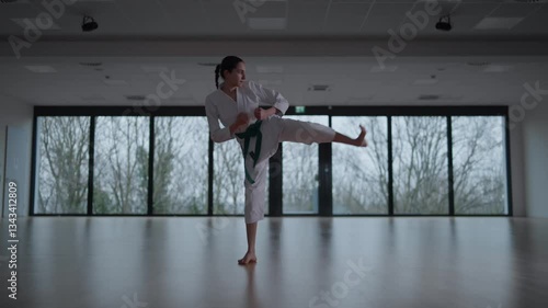 Woman training Karate in the dark, with big windows in the back