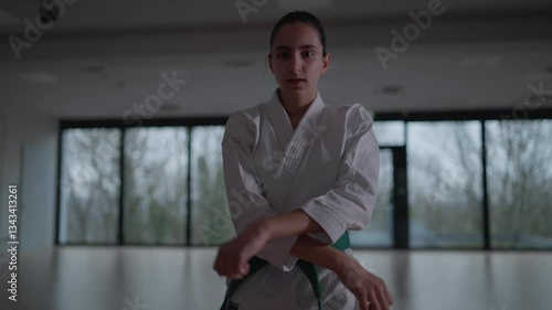 Woman training Karate in the dark, with big windows in the back