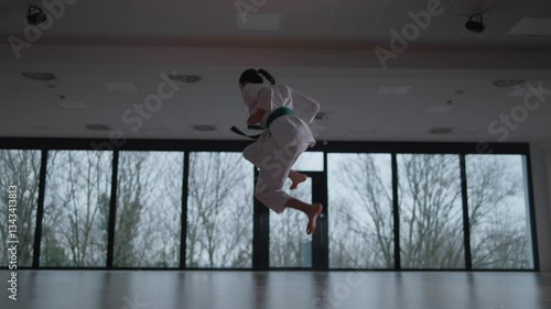 Woman training Karate in the dark, with big windows in the back