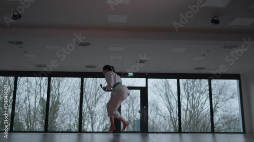 Woman training Karate in the dark, with big windows in the back