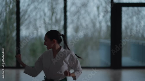Woman training Karate in the dark, with big windows in the back