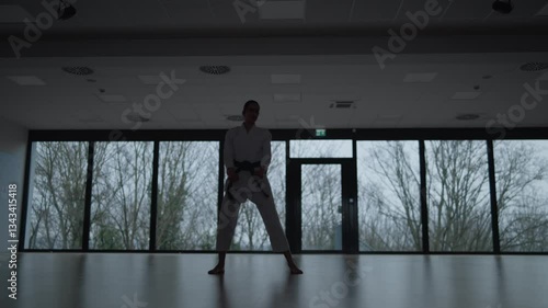 Woman training Karate in the dark, with big windows in the back