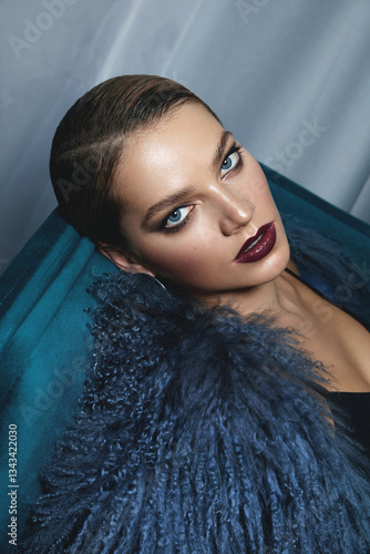 Portrait of a beautiful young woman in evening make-up and a luxurious trendy fur coat. Advertisement of fashionable clothes and decorative cosmetics. Luxurious lifestyle, trends. Smooth hairstyle.