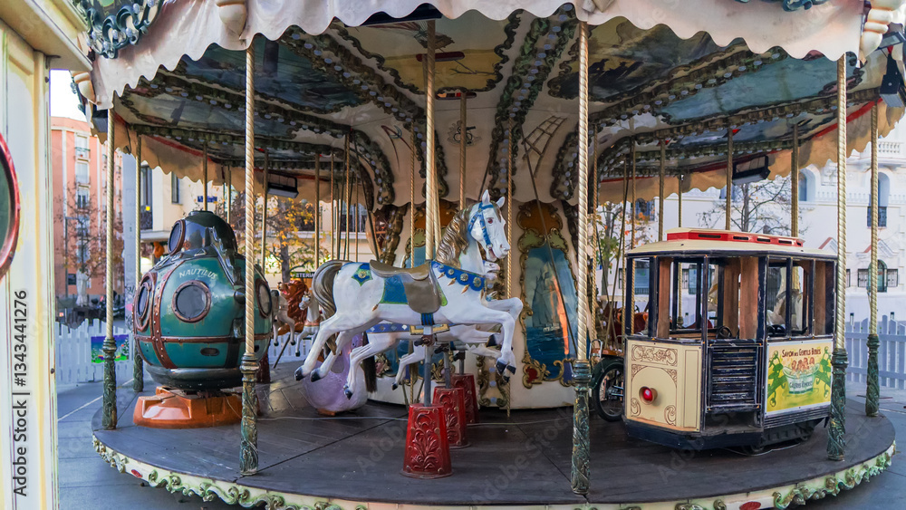 Empty retro carousel with horses and a carriage waiting for children to ride