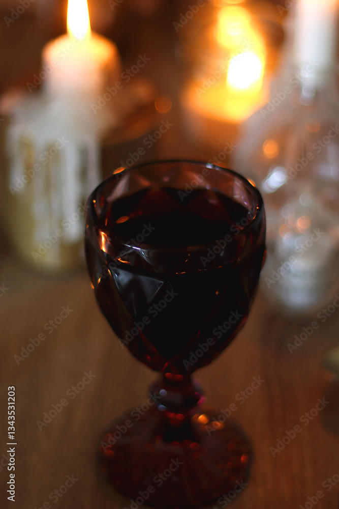 Books, lit candles, red wine, snacks and various deocration on the table. Dark academia or Halloween concept. Selective focus.